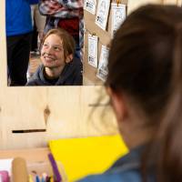 Student smiles and looks up as student merchant draws portrait during Student Small Business Market.